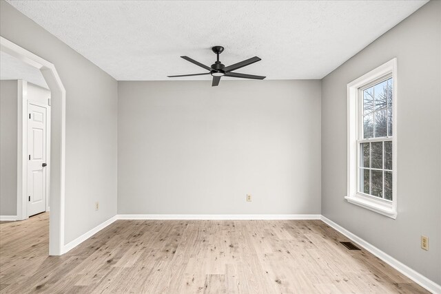 empty room with light wood-style floors, visible vents, ceiling fan, and baseboards