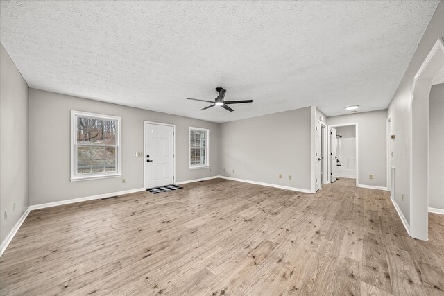 unfurnished living room featuring light wood finished floors, baseboards, and a ceiling fan