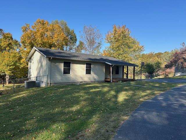 view of front of home featuring a front yard, cooling unit, and fence