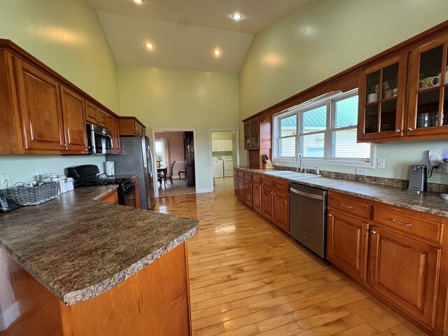 1032 Kendall Smith Rd, Pikeville, TN 37367 - kitchen with stainless steel appliances, high vaulted ceiling, washing machine and clothes dryer, dark countertops, and brown cabinetry