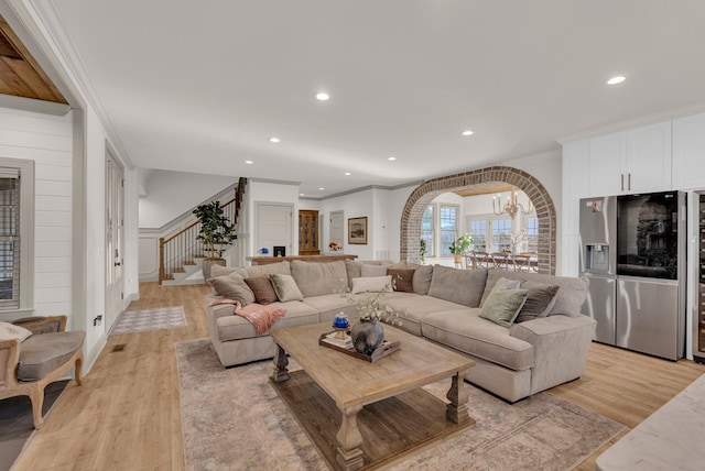 living room featuring light wood-type flooring, stairway, ornamental molding, and recessed lighting