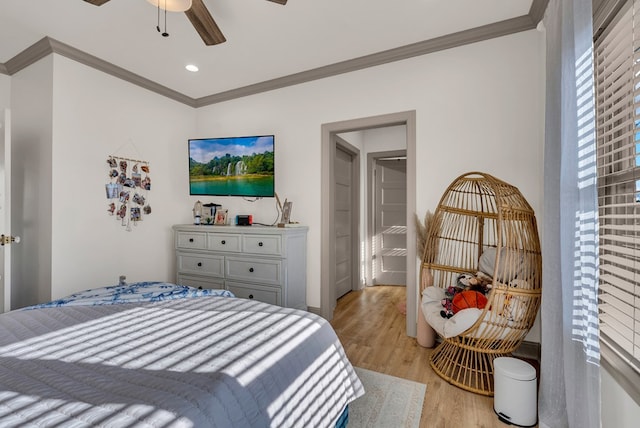 bedroom with light wood finished floors, ornamental molding, and a ceiling fan