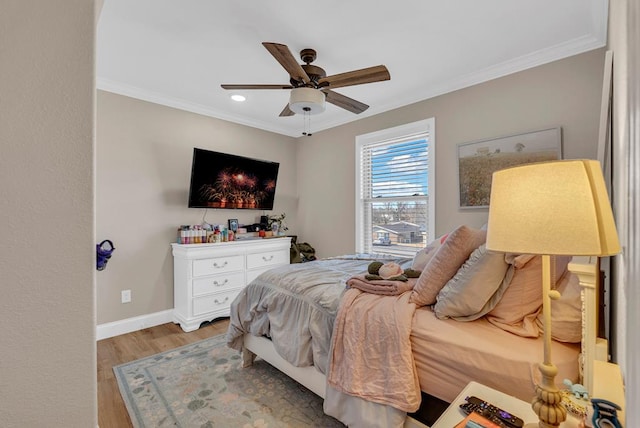 bedroom featuring light wood finished floors, a ceiling fan, baseboards, and crown molding