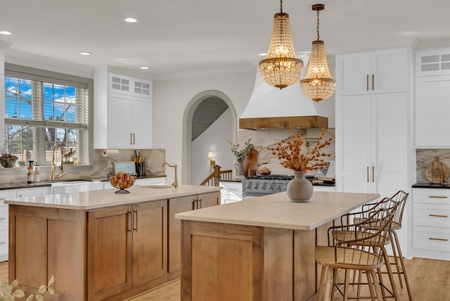 kitchen featuring white cabinets, glass insert cabinets, decorative light fixtures, a center island, and light countertops