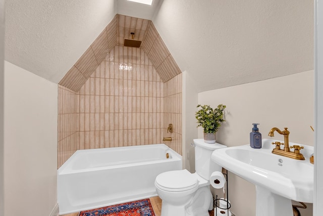 full bath with vaulted ceiling with skylight, toilet, tub / shower combination, a textured ceiling, and a sink