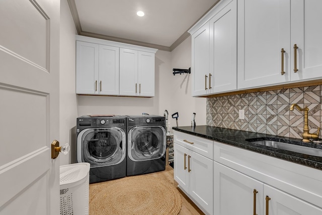 clothes washing area with cabinet space, washer and clothes dryer, ornamental molding, light wood-type flooring, and a sink