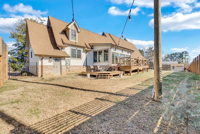 rear view of property with roof with shingles, a lawn, board and batten siding, fence, and a wooden deck