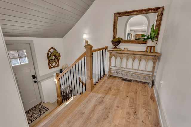 foyer featuring vaulted ceiling, light wood finished floors, wood ceiling, and baseboards