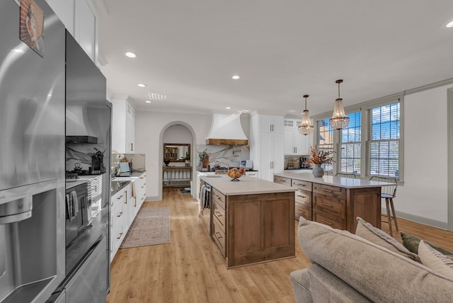 kitchen featuring custom range hood, light countertops, white cabinets, and a kitchen island