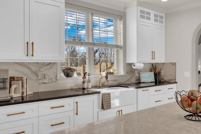 bar with tasteful backsplash, arched walkways, crown molding, and a sink