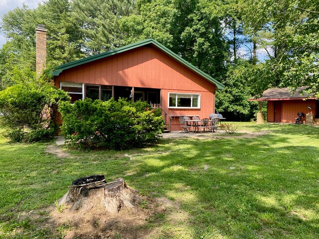 151 Dykes Ln, Crossville, TN 38571 - back of property featuring a yard, a patio, a chimney, and an outdoor structure