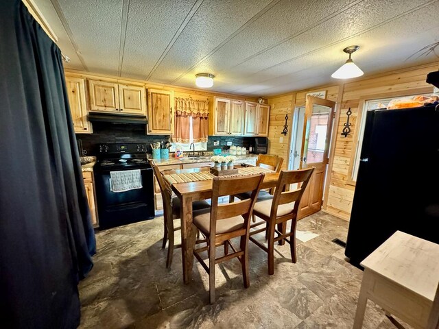 151 Dykes Ln, Crossville, TN 38571 - kitchen with black appliances, under cabinet range hood, a sink, light countertops, and wooden walls