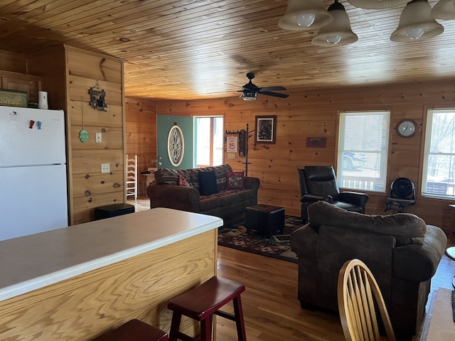 living room featuring wood finished floors, wooden walls, a healthy amount of sunlight, and wooden ceiling