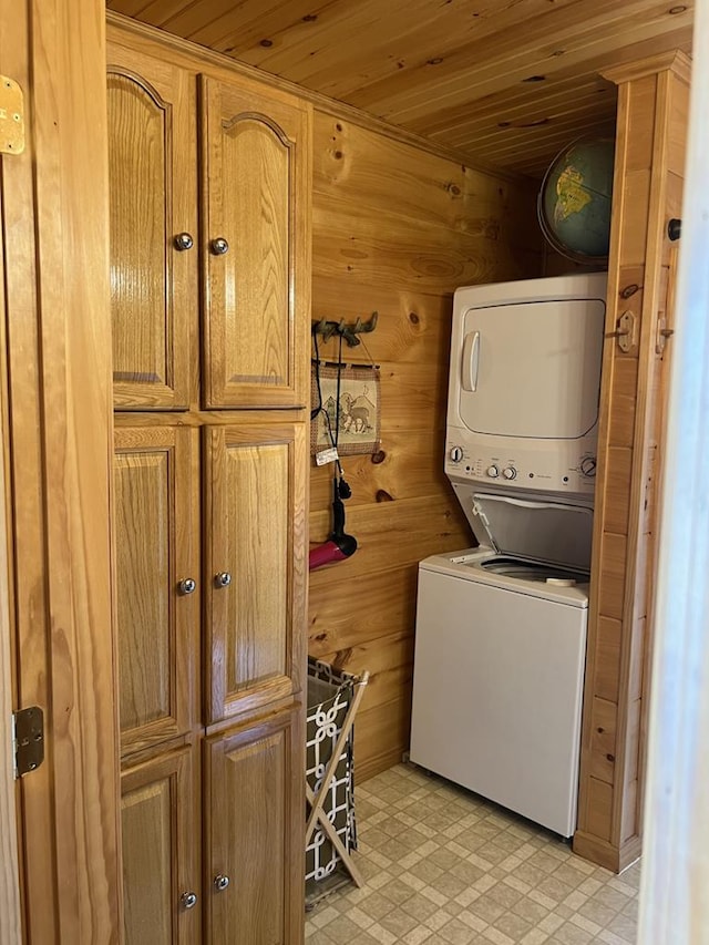 washroom featuring wooden walls, light floors, wood ceiling, stacked washer and dryer, and cabinet space