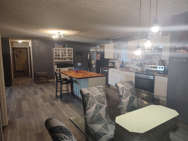 kitchen with white cabinets, butcher block counters, a kitchen island, hanging light fixtures, and stainless steel appliances