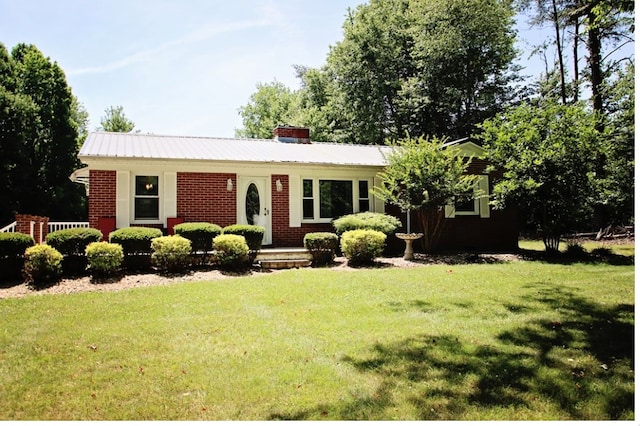 ranch-style house with brick siding, a chimney, and a front yard