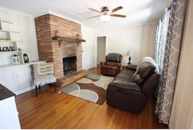 living room with a brick fireplace, crown molding, and wood finished floors