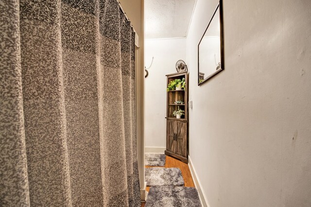 interior space with a textured ceiling, baseboards, and wood finished floors