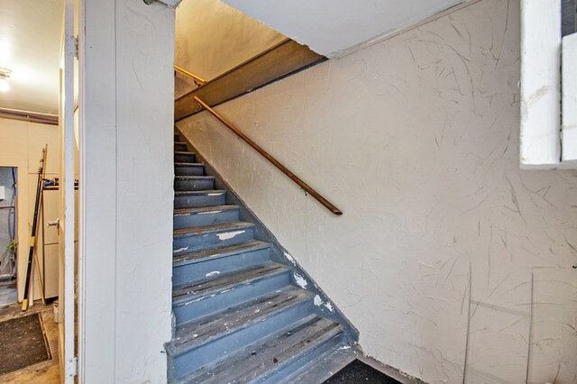 staircase featuring a textured wall