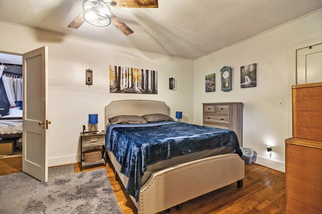 bedroom with dark wood finished floors, a textured ceiling, baseboards, and ceiling fan