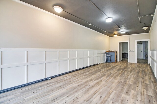 unfurnished room featuring wainscoting, a decorative wall, and wood finished floors