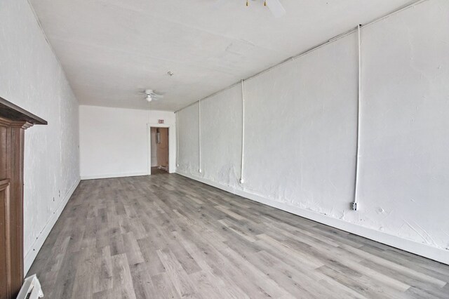 spare room featuring ceiling fan, a baseboard heating unit, and light wood-style flooring