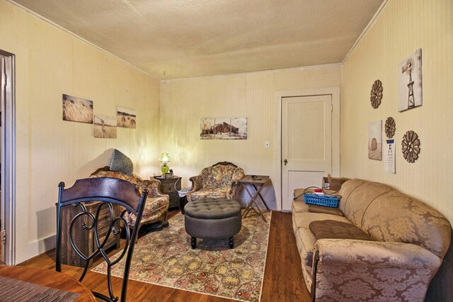 living area with a textured ceiling, ornamental molding, and wood finished floors