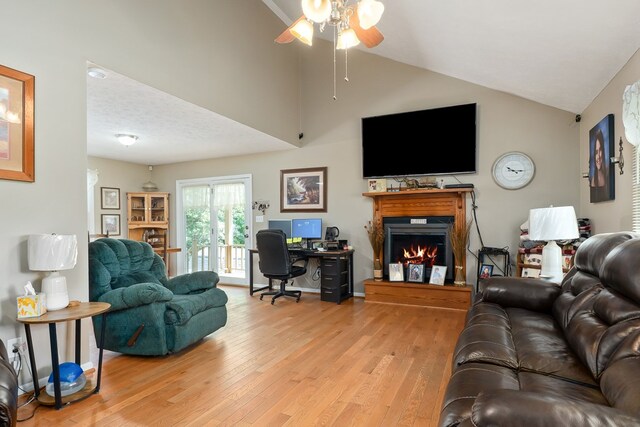 2876 Hilham Hwy, Hilham, TN 38568 - living area featuring a desk, ceiling fan, a warm lit fireplace, wood finished floors, and vaulted ceiling