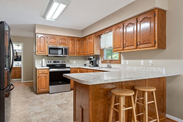 2876 Hilham Hwy, Hilham, TN 38568 - kitchen featuring appliances with stainless steel finishes, a peninsula, light countertops, and brown cabinets