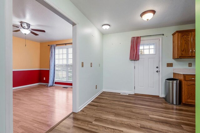 interior space featuring light wood-style floors, ceiling fan, and baseboards