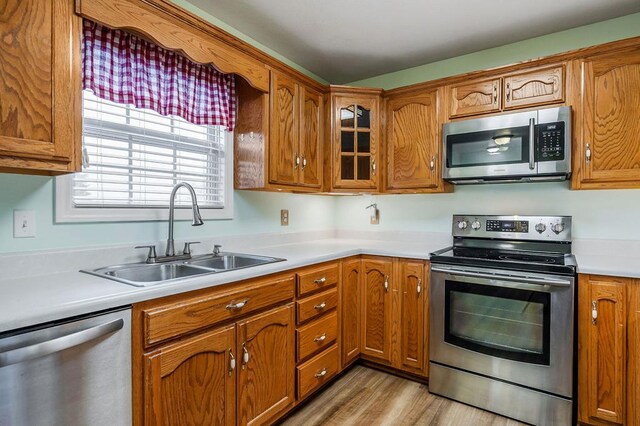 kitchen with stainless steel appliances, brown cabinets, light countertops, and a sink