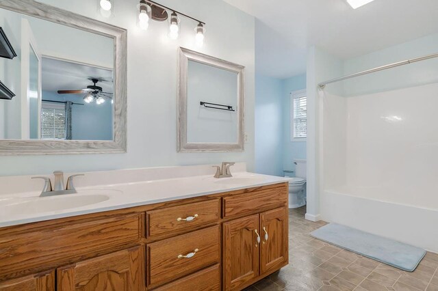 bathroom with toilet, ceiling fan, double vanity, and a sink