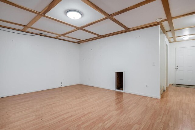 empty room featuring light wood-type flooring, coffered ceiling, and baseboards