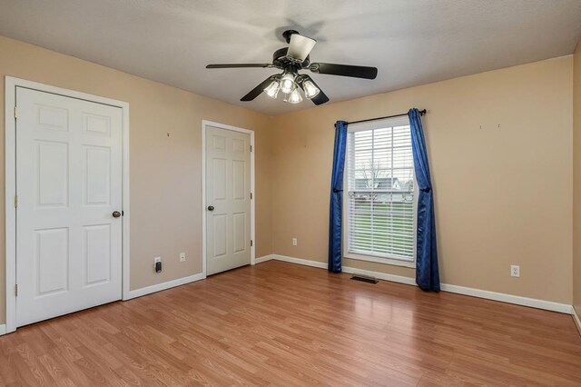 unfurnished bedroom with a ceiling fan, light wood-type flooring, visible vents, and baseboards