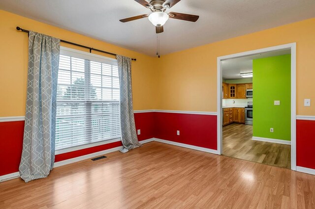 unfurnished room featuring visible vents, ceiling fan, light wood-style flooring, and baseboards