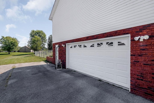 garage with fence and aphalt driveway