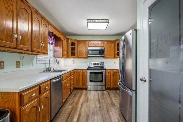 kitchen featuring brown cabinets, glass insert cabinets, stainless steel appliances, and light countertops