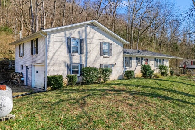 split level home featuring an attached garage, brick siding, and a front yard