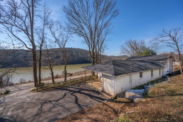 view of side of home featuring brick siding, a water view, and fence