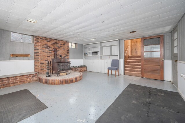 unfurnished living room featuring a wood stove and stairs