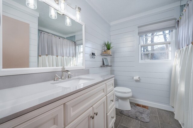 full bathroom with visible vents, toilet, a textured ceiling, vanity, and baseboards