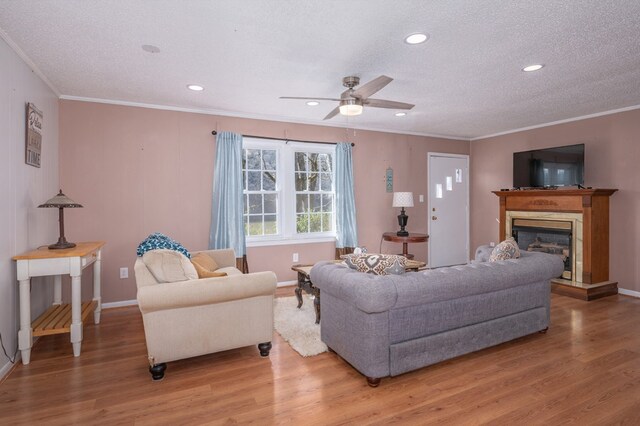 living area featuring a fireplace with raised hearth, a textured ceiling, wood finished floors, and crown molding