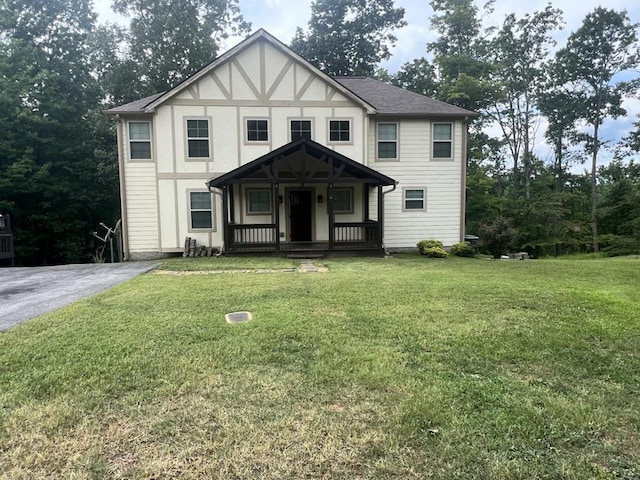 view of front of property featuring covered porch, roof with shingles, driveway, and a front lawn