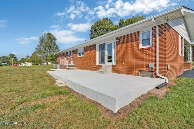 back of house featuring entry steps, brick siding, and a yard