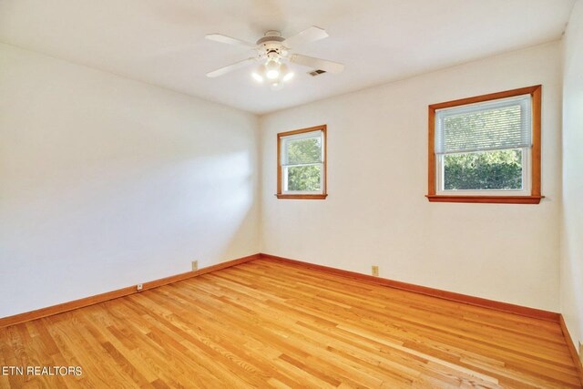 empty room with ceiling fan, light wood-type flooring, visible vents, and baseboards