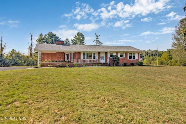 single story home with a porch, a front yard, brick siding, and a chimney