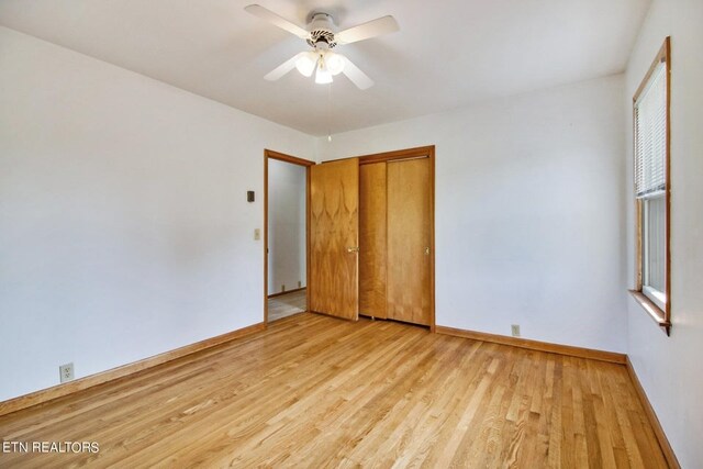 unfurnished bedroom with a ceiling fan, a closet, light wood-style flooring, and baseboards