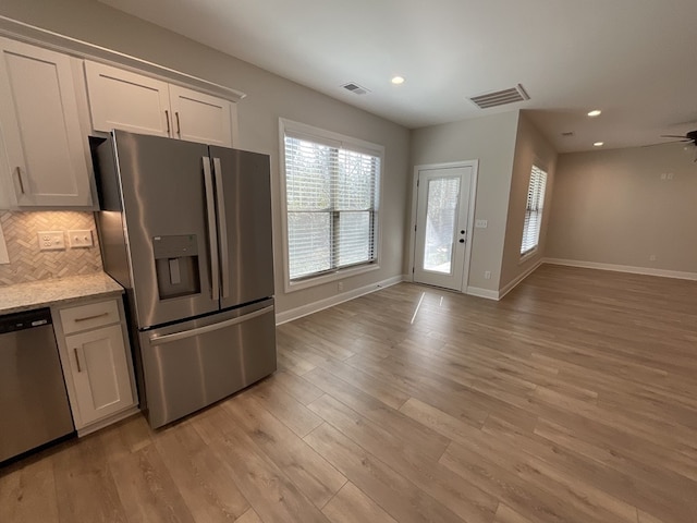 kitchen with visible vents, backsplash, appliances with stainless steel finishes, open floor plan, and white cabinetry