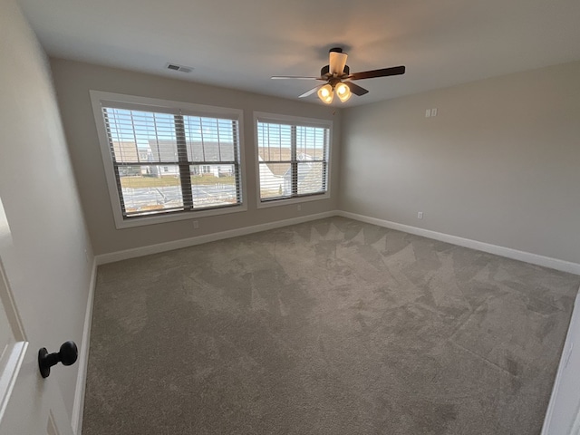 carpeted empty room featuring a ceiling fan, visible vents, and baseboards