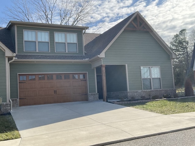 craftsman house with a garage, brick siding, driveway, and roof with shingles